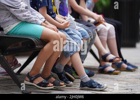 Hamburg, Deutschland. 13.. Juli 2022. Kinder sitzen auf einer Bank in den Innenhöfen der Stadt. Kredit: Marcus Brandt/dpa/Alamy Live Nachrichten Stockfoto
