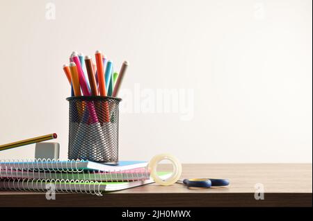 Schulbedarf mit Stift mit Markern auf Notizbüchern mit Werkzeugen auf Holzschreibtisch. Vorderansicht. Horizontale Zusammensetzung. Stockfoto