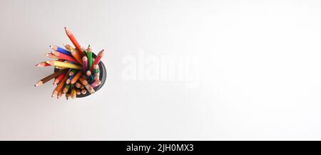 Hintergrund mit Gruppe von Buntstiften verschiedener Farben in einem Stifthalter auf einem weißen. Draufsicht. Horizontale Panoramakomposition. Stockfoto