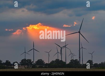 Mallnow, Deutschland. 13.. Juli 2022. Durch eine Lücke in den Wolken über der Landschaft mit Windturbinen scheint der farbenfrohe Sonnenuntergang. Quelle: Patrick Pleul/dpa/Alamy Live News Stockfoto