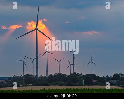 Mallnow, Deutschland. 13.. Juli 2022. Durch eine Lücke in den Wolken über der Landschaft mit Windturbinen scheint der farbenfrohe Sonnenuntergang. Quelle: Patrick Pleul/dpa/Alamy Live News Stockfoto