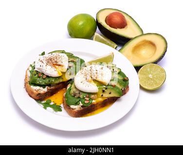 Frisch zubereitetes pochiertes Ei und Avocado-Toast isoliert auf weißem Hintergrund Stockfoto