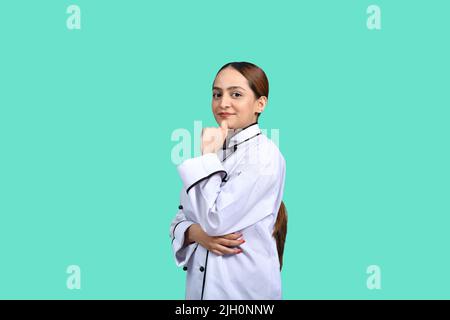 Die Köchin posiert mit der Hand am Kinn und denkt positiv zum Kochen Stockfoto