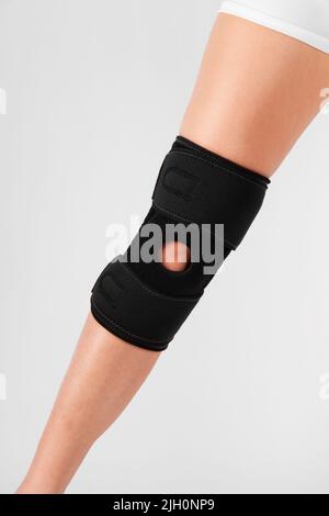 Kniestützenstrebe am Bein isoliert auf weißem Hintergrund. Elastische orthopädische Orthese. Anatomische Hosenträger für Kniefixierung, Verletzungen und Schmerzen. Schutz Stockfoto
