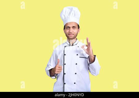 Der Chefkoch zeigt das Daumen-hoch-Zeichen und das perfekte Zeichen für Anerkennung Stockfoto