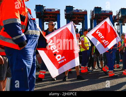 Hamburg, Deutschland. 14.. Juli 2022. Arbeiter mit Verdi-Fahnen protestieren während eines Warnstreiks vor dem Container Terminal Burchardkai (CTA) der HHLA (Hamburger Hafen und Logistik AG). Im Konflikt um die Bezahlung von Hafenarbeitern in den großen deutschen Nordseehäfen ist noch immer keine Einigung in Sicht. Die Gewerkschaft Verdi hat Hafenarbeiter zu einem 48-stündigen Warnstreik aufgefordert. Quelle: Christian Charisius/dpa/Alamy Live News Stockfoto