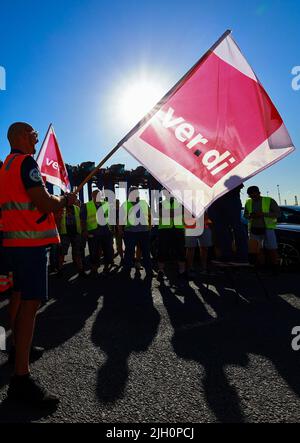 Hamburg, Deutschland. 14.. Juli 2022. Arbeiter mit Verdi-Fahnen protestieren während eines Warnstreiks vor dem Container Terminal Burchardkai (CTA) der HHLA (Hamburger Hafen und Logistik AG). Im Konflikt um die Bezahlung von Hafenarbeitern in den großen deutschen Nordseehäfen ist noch immer keine Einigung in Sicht. Die Gewerkschaft Verdi hat Hafenarbeiter zu einem 48-stündigen Warnstreik aufgefordert. Quelle: Christian Charisius/dpa/Alamy Live News Stockfoto