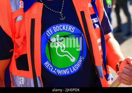 Hamburg, Deutschland. 14.. Juli 2022. Ein Arbeiter mit dem Logo der ITF - International Transport Workers' Federation auf seinem T-Shirt steht während eines Warnstreiks vor dem Container Terminal Burchardkai (CTA) der HHLA (Hamburger Hafen und Logistik AG). Im Streit um die Bezahlung von Hafenarbeitern in den großen deutschen Nordseehäfen ist noch keine Einigung in Sicht. Die Gewerkschaft Verdi hat Hafenarbeiter zu einem 48-stündigen Warnstreik aufgefordert. Quelle: Christian Charisius/dpa/Alamy Live News Stockfoto