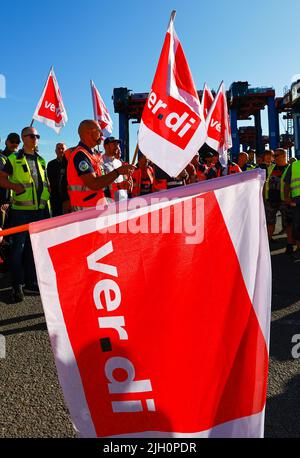 Hamburg, Deutschland. 14.. Juli 2022. Arbeiter mit Verdi-Fahnen protestieren während eines Warnstreiks vor dem Container Terminal Burchardkai (CTA) der HHLA (Hamburger Hafen und Logistik AG). Im Konflikt um die Bezahlung von Hafenarbeitern in den großen deutschen Nordseehäfen ist noch immer keine Einigung in Sicht. Die Gewerkschaft Verdi hat Hafenarbeiter zu einem 48-stündigen Warnstreik aufgefordert. Quelle: Christian Charisius/dpa/Alamy Live News Stockfoto