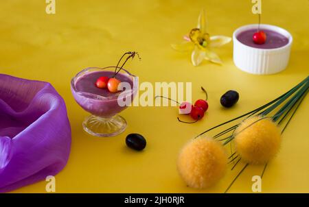 Jamun Mousse, Malabar Plum Fruit Mousse mit Kirschenauflage. Frisches, hausgemachtes Dessert aus Jamun. Sommerpudding auf dunkelgelbem Hintergrund, Nahaufnahme. Stockfoto