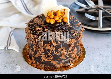 Kuchen zum Feiern. Geburtstagskuchen mit Krokus auf steinernem Hintergrund. Mit Schokolade überzogene Kuchen. Nahaufnahme Stockfoto