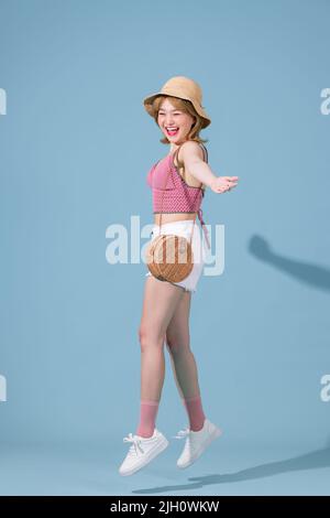 Hübsche junge Frau springt mit vor dem blauen Hintergrund Stockfoto