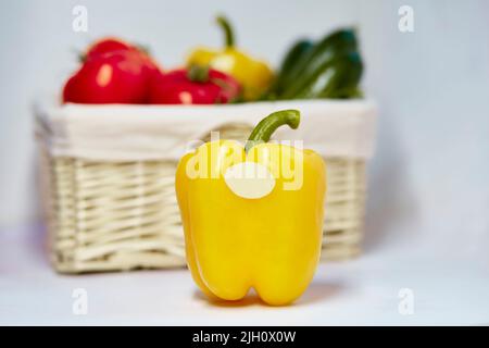 Nachbau des Etiketts auf der Paprika aus nächster Nähe. Aufkleber Produkt für Text oder Preis. Korb mit Gemüse auf dem Hintergrund. Bio-Landwirtschaftsprodukte vom lokalen Markt Stockfoto