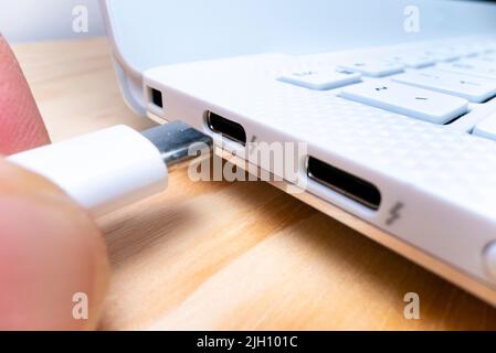 Nahaufnahme der Makroansicht des Einsteckens eines USB-Kabels vom Typ C in den Anschluss eines Laptops, aufgenommen mit Makrosondenobjektiv Stockfoto