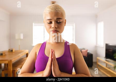 Bild einer Birazialfrau, die zu Hause Yoga praktiziert Stockfoto