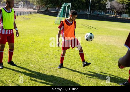 Kaukasischer männlicher Spieler, der auf dem Rasen auf dem Spielplatz einen Teamkollegen beim Freestyle-Fußball ansieht Stockfoto