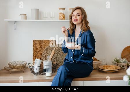 Schönes Mädchen in Pyjamas essen Getreide in der Küche Stockfoto