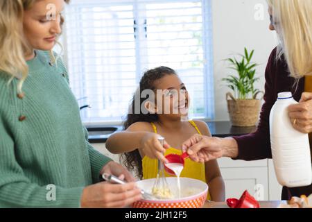 Multirassische glückliche, mehrgenerationenige weibliche Familie, die zu Hause in der Küche Lebensmittel zubereitet Stockfoto