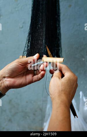 Hand des Fischers repariert ein Netz mit einem Messer Stockfoto