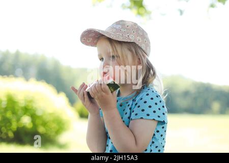 Nettes kleines Mädchen, das im Sommer Wassermelone im Freien isst. Kind und Wassermelone im Sommer. Stockfoto