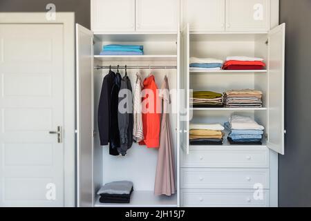 Modernes Ankleidezimmer, ordentlich aufgehängt Kleidung an Kleiderbügel und Regale im Schrank Stockfoto