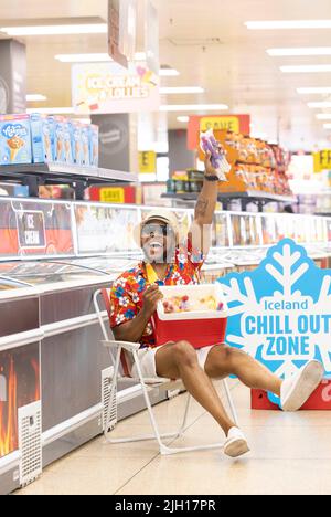 REDAKTIONELLE VERWENDUNG NUR Anton Thompson in der „Chill-out Zone“ eines isländischen Supermarkts in Islington, einem Sitzbereich im Gefriergang, der Kunden bei der aktuellen Hitzewelle dabei helfen soll, sich abzukühlen. Bilddatum: Donnerstag, 14. Juli 2022. Stockfoto