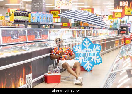 REDAKTIONELLE VERWENDUNG NUR Anton Thompson in der „Chill-out Zone“ eines isländischen Supermarkts in Islington, einem Sitzbereich im Gefriergang, der Kunden bei der aktuellen Hitzewelle dabei helfen soll, sich abzukühlen. Bilddatum: Donnerstag, 14. Juli 2022. Stockfoto