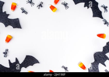 Halloween Rahmen Hintergrund. Fledermaus- und Spinnendekorationen mit traditionellem Trick o Treat Candy Corn auf weißem Hintergrund. Halloween Grußkarte. Flat la Stockfoto