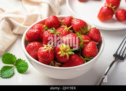 Erdbeeren in einer weißen Schale auf hellem Hintergrund. Seitenansicht, Nahaufnahme. Stockfoto