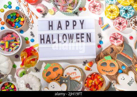 Set aus verschiedenen klassischen Halloween-Leckereien auf weißem Hintergrund. Auswahl Sortiment traditionelle Kekse, Lebkuchen, Süßigkeiten, Süßigkeiten und Deko-Kürbisse. Stockfoto