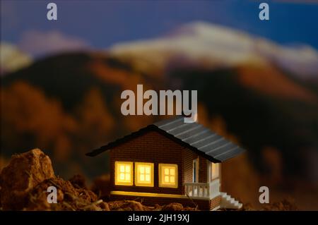 Kleine bewohnte Hütte, die mitten in der Natur liegt und von der aus man einige verschneite Berge im Hintergrund sehen kann Stockfoto