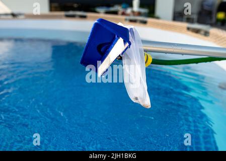 Reinigung des Hauspools im Garten mit einer Bürste, Reinigung und Wartung des Hauptpools. Stockfoto