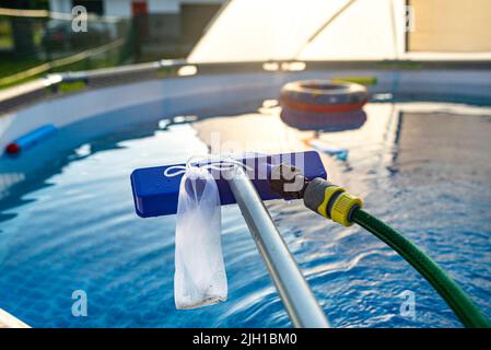 Reinigung des Hauspools im Garten mit einer Bürste, Reinigung und Wartung des Hauptpools. Stockfoto