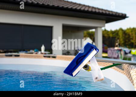 Reinigung des Hauspools im Garten mit einer Bürste, Reinigung und Wartung des Hauptpools. Stockfoto