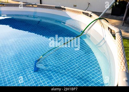 Reinigung des Hauses Pool im Garten mit einer Bürste, ziehen Schmutz vom Boden des Pools. Stockfoto