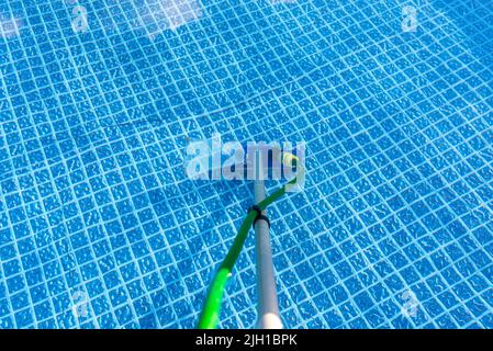 Reinigung des Hauses Pool im Garten mit einer Bürste, ziehen Schmutz vom Boden des Pools. Stockfoto