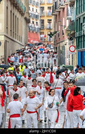 Pamplona, SPANIEN - Juli 06 2022: Straßen von Pamplona am Anfang von San Fermin. Menschen, die in weiß und rot gekleidet sind, gehen zum Rathausplatz. Stockfoto
