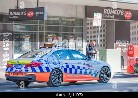 Ein Polizeifahrzeug von New South Wales, Highway Patrol, mit angezündter Beleuchtung, hielt mit einem Beamten an, der neben dem Fahrzeug in Parramatta, Australien, stand Stockfoto