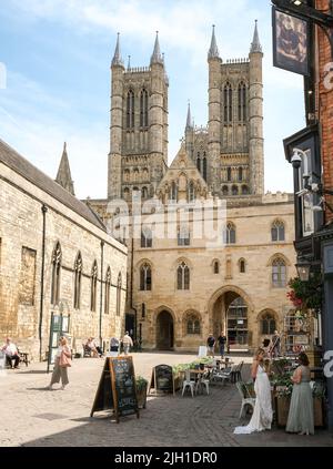 Lincoln, Lincolnshire, Großbritannien, Juni 16 2022. Elegant gekleidete Damen mit formellen Kleidern deuten auf eine bevorstehende Hochzeitsfeier vor der Lincoln Cathedral hin Stockfoto