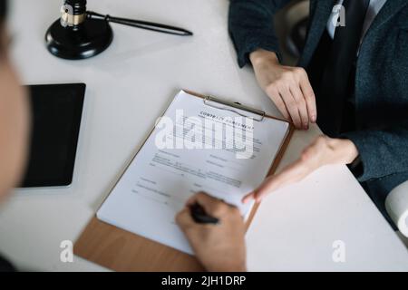 Rechtsanwalt Rechtsberater präsentiert dem Mandanten einen unterzeichneten Vertrag mit Gavel und Rechtsrecht. Justiz und Rechtsanwalt Business Partnership Meeting Konzept. Stockfoto
