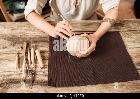 Ton Schüssel Thema dekorieren, Töpferei. Das Schnitzen von handgemachtem Geschirr mit speziellen Werkzeugen Stockfoto