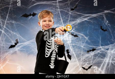 Junge mit Süßigkeiten und Taschenlampe an halloween Stockfoto