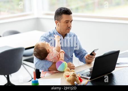 Vater mit Baby, der im Heimbüro arbeitet Stockfoto