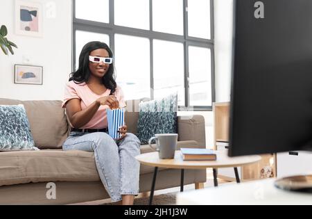 Glückliche afroamerikanische Frau, die zu Hause Fernsehen schaut Stockfoto