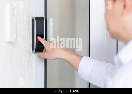 Nahaufnahme. Die Hand eines jungen Mannes in einem weißen Hemd ruft die Sprechanlage des Hauses an, drückt den Knopf, wartet auf das Öffnen der Tür. Stockfoto