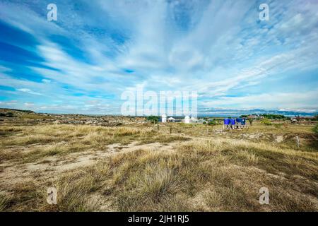 Eine Aufnahme eines trockenen Graslandes in einer Tatacoa-Wüste mit schönem bewölktem Himmel in Villavieja, Kolumbien Stockfoto