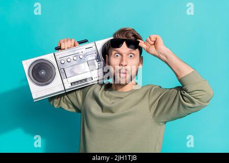 Foto von aufgeregt verrückt funky Mann nehmen Sonnenglas halten Boombox tragen Pullover isoliert blauen Hintergrund Stockfoto