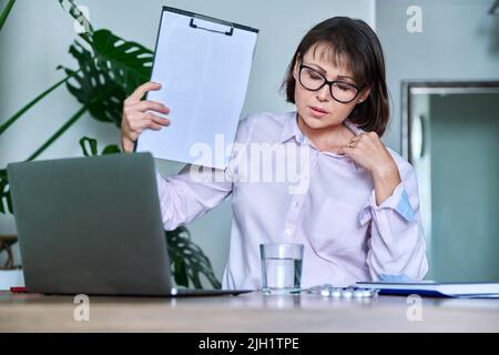 Frau mittleren Alters, die an Hitze leidet, überhitzt, durch Ventilator und Ventilator gekühlt Stockfoto