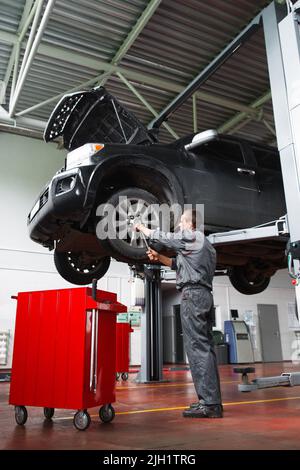 Männlicher Mechaniker, der Service-Wartung für das Auto macht Stockfoto
