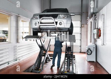 Mechaniker überprüfen das Fahrwerk des angehobenen Fahrzeugs Stockfoto